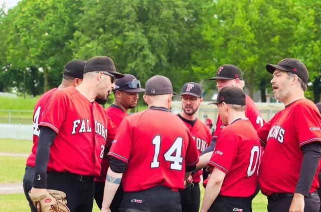 Spelers van Falcons in het rode shirt overleggen op het veld