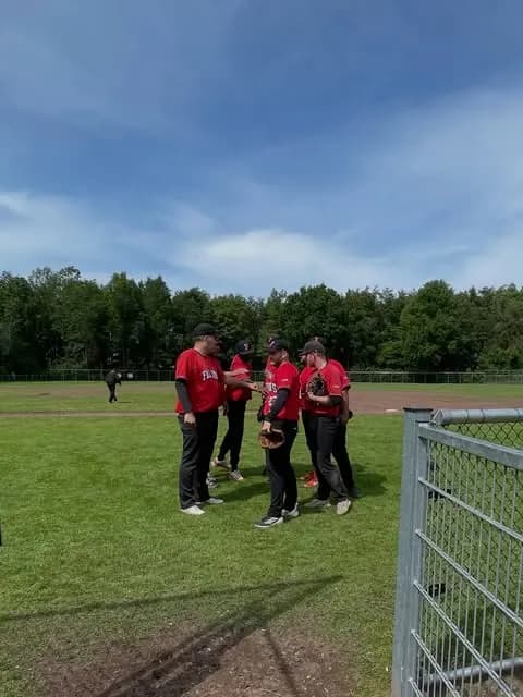 Spelers van Falcons in rode shirts overleggen op het gras