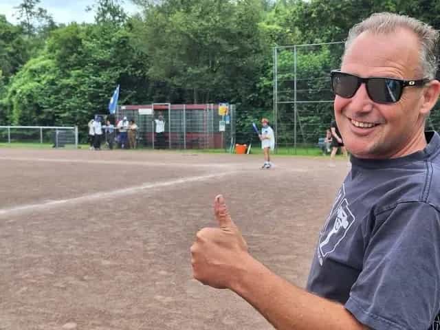 Vrijwilliger van Falcons langs het veld, met spelers op de achtergrond